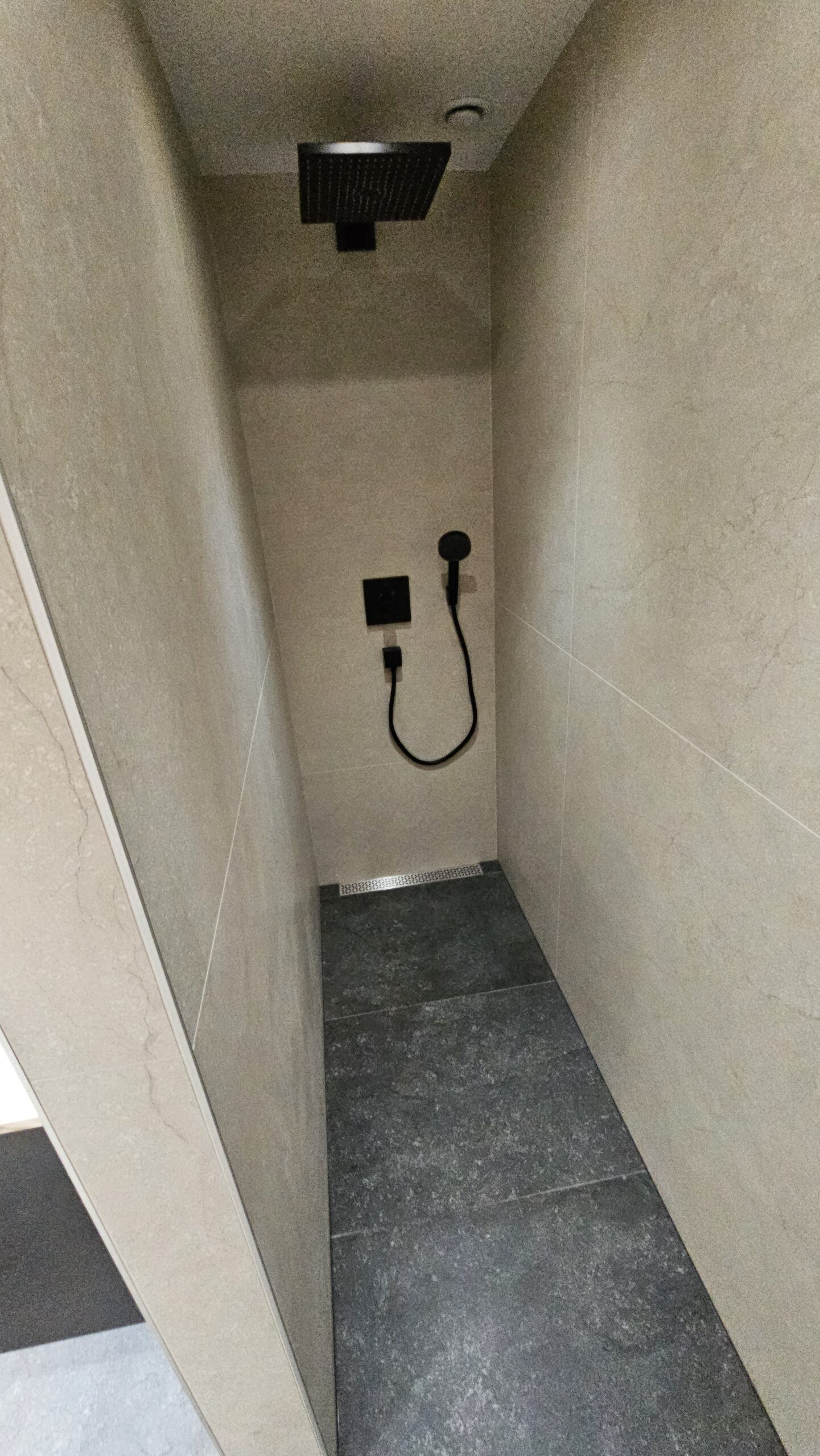 Douche à l'italienne avec robinetterie noire mate et carrelage grand format