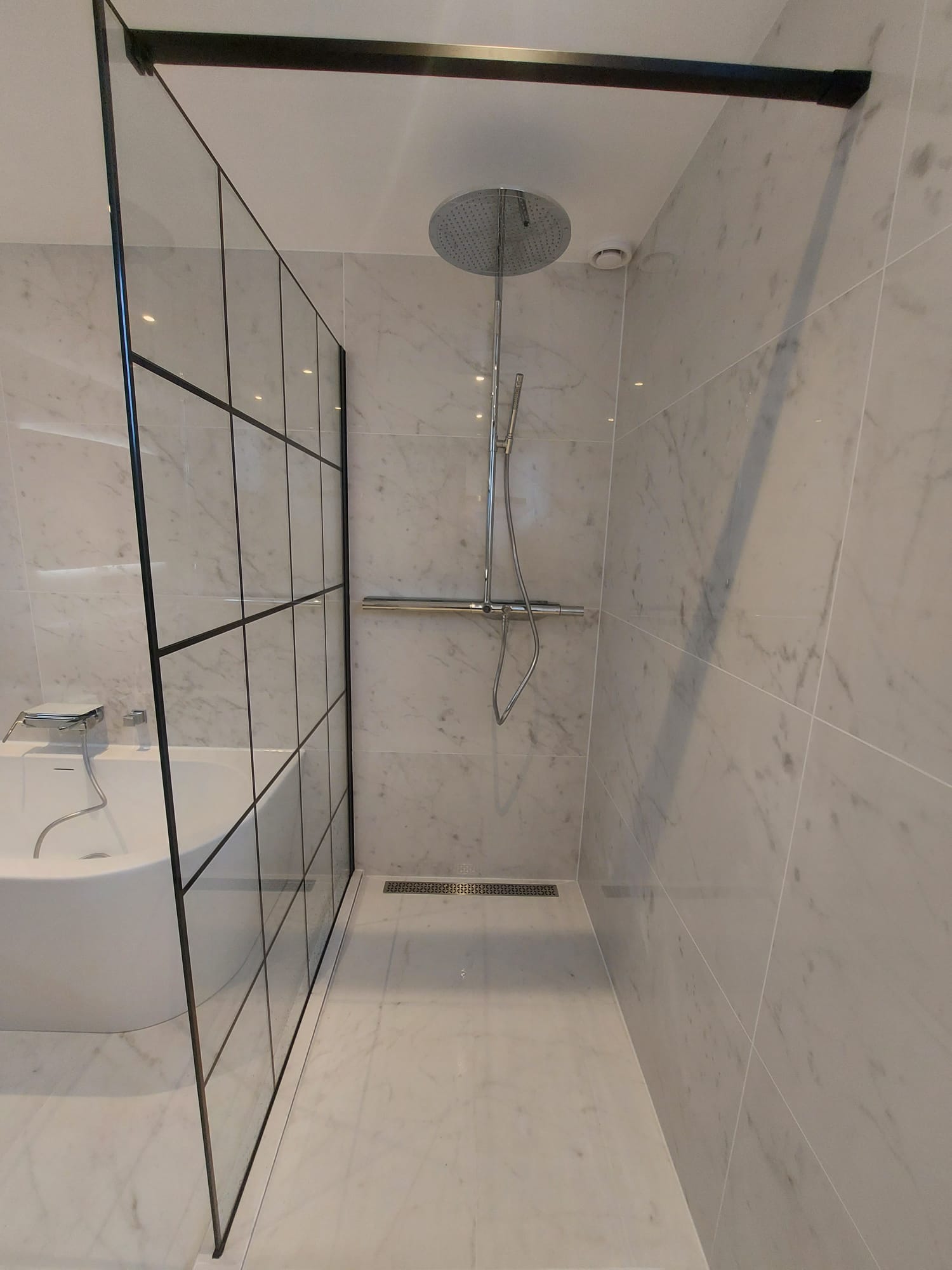 Douche à l'italienne en marbre blanc avec paroi vitrée