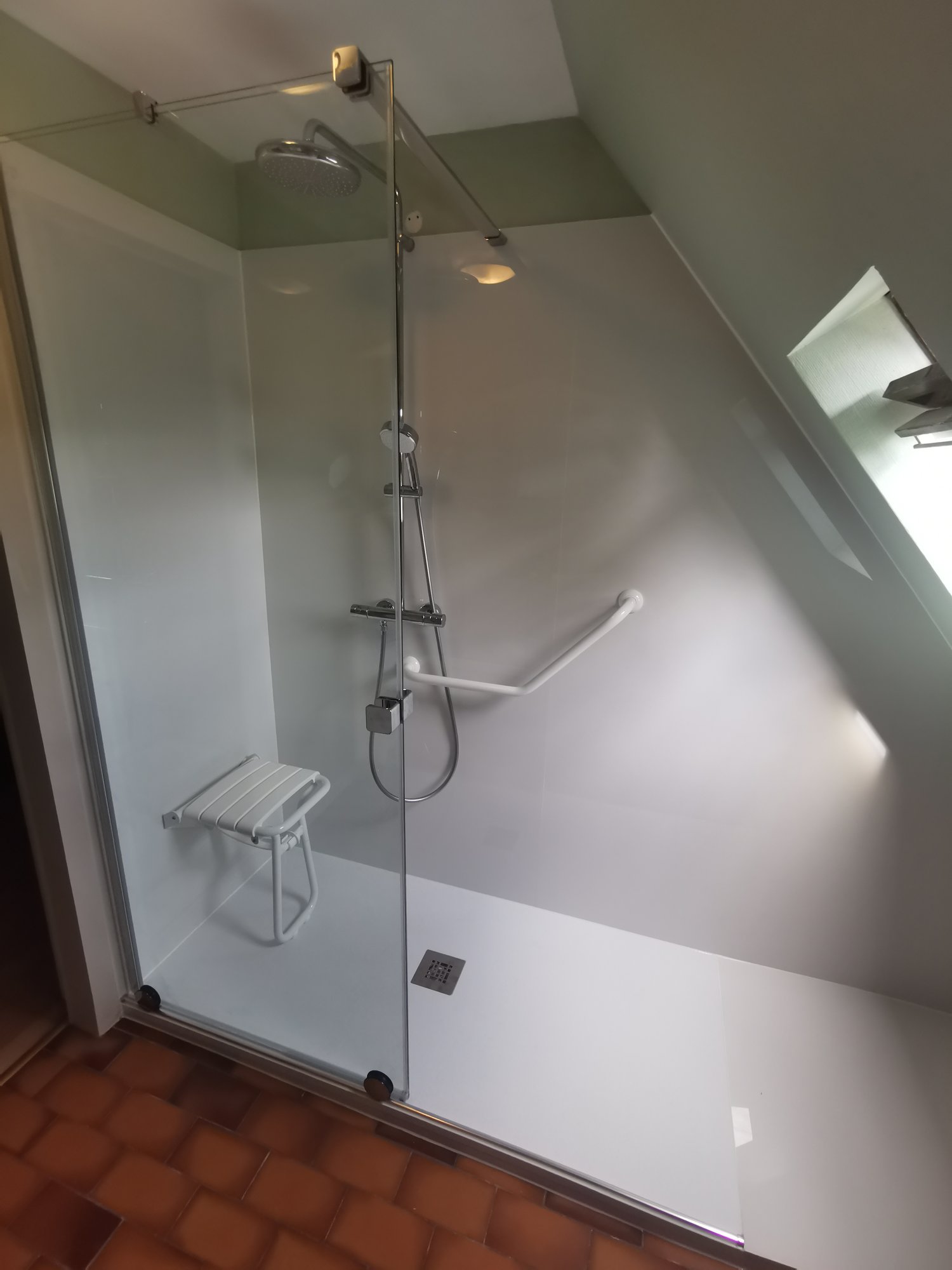 Salle de bain PMR sous pente avec siège de douche rabattable et barre d'appui – réalisation RENOVO