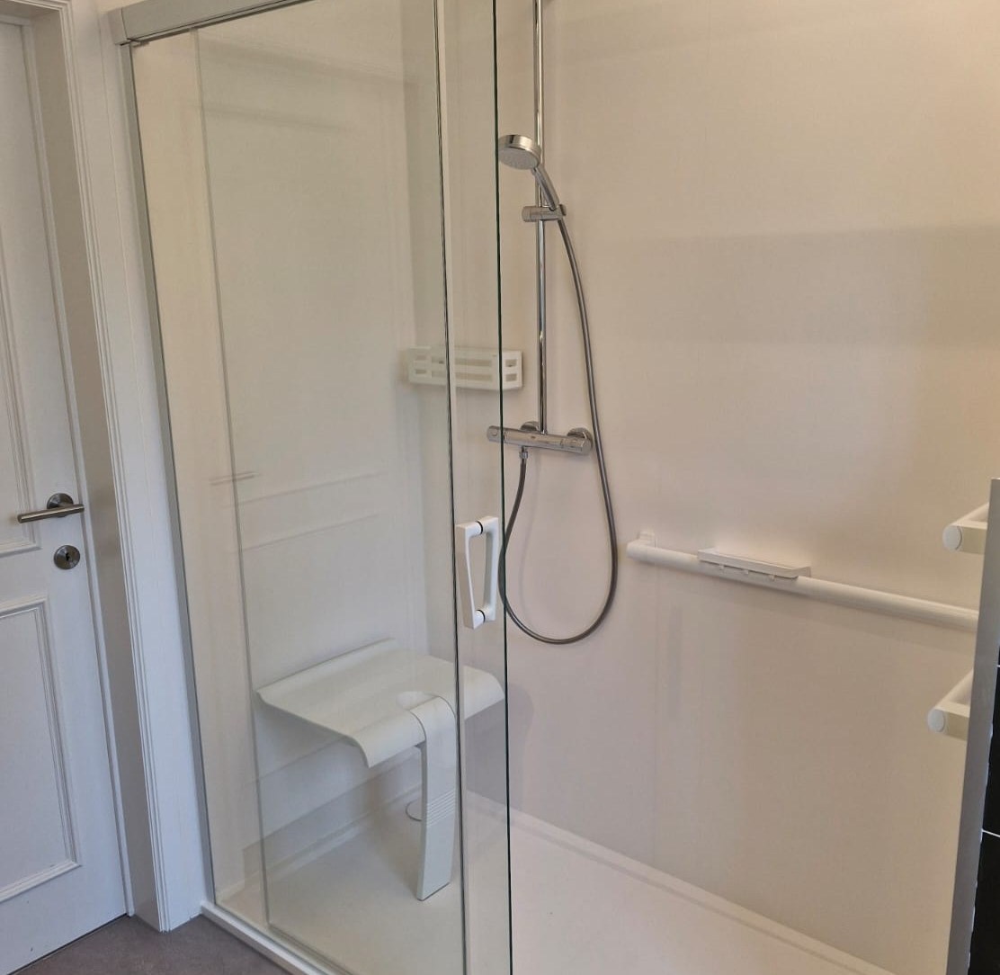 Douche PMR avec paroi vitrée, siège rabattable et barre d'appui – réalisation RENOVO